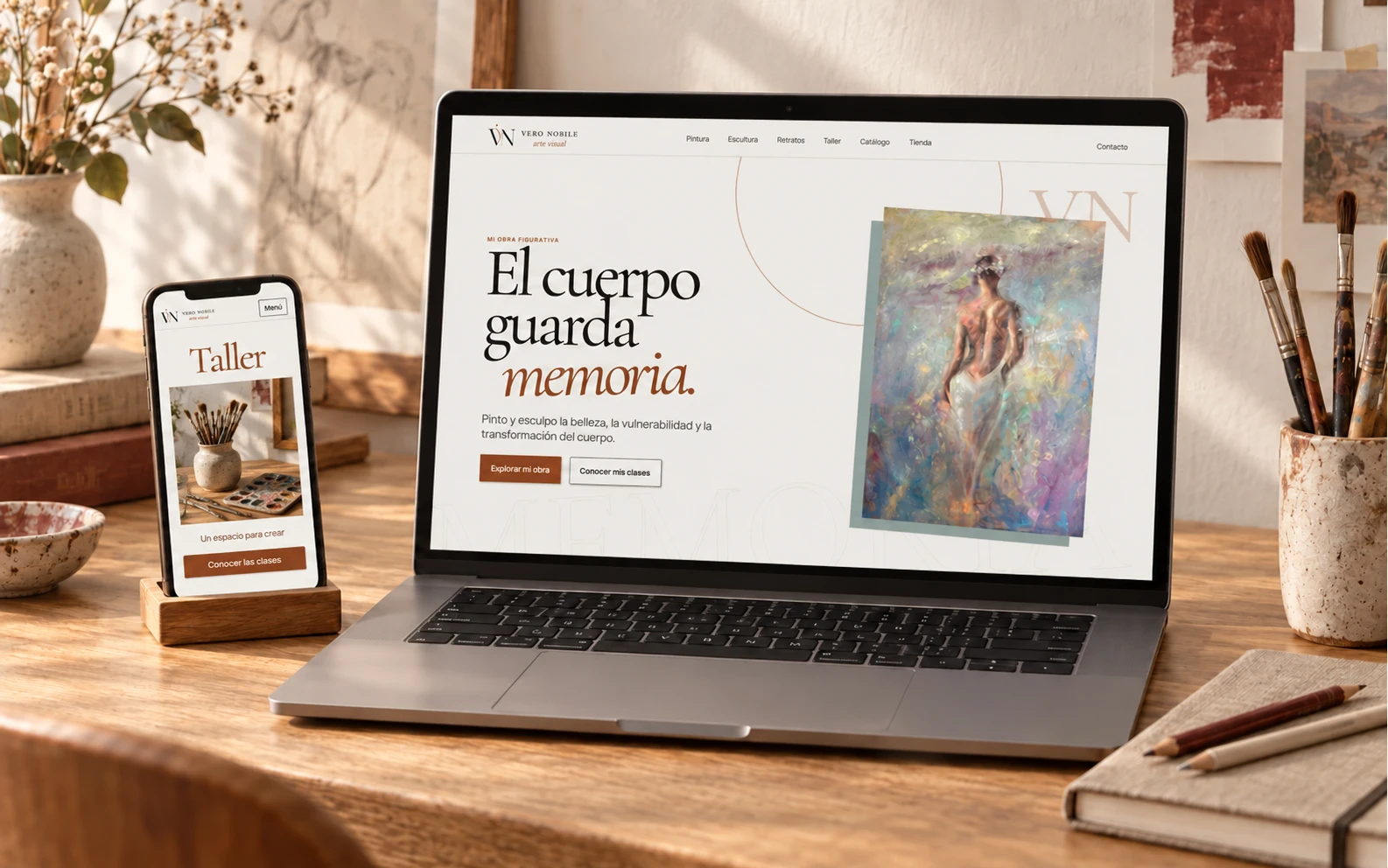 Composición de la web de Vero Nobile en computadora y celular sobre un escritorio de artista en una escena conceptual